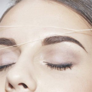 Woman getting threading done on eyebrows